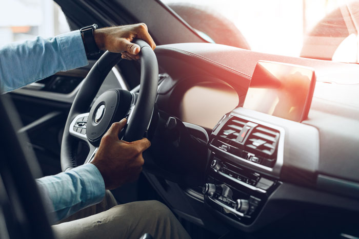 Male hands holding steering wheel of a car